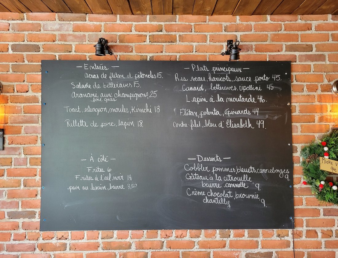 Le tableau noir du Zélé accroché au mur de brique : entrées, plats principaux, à-côtés et desserts écrits à la craie
