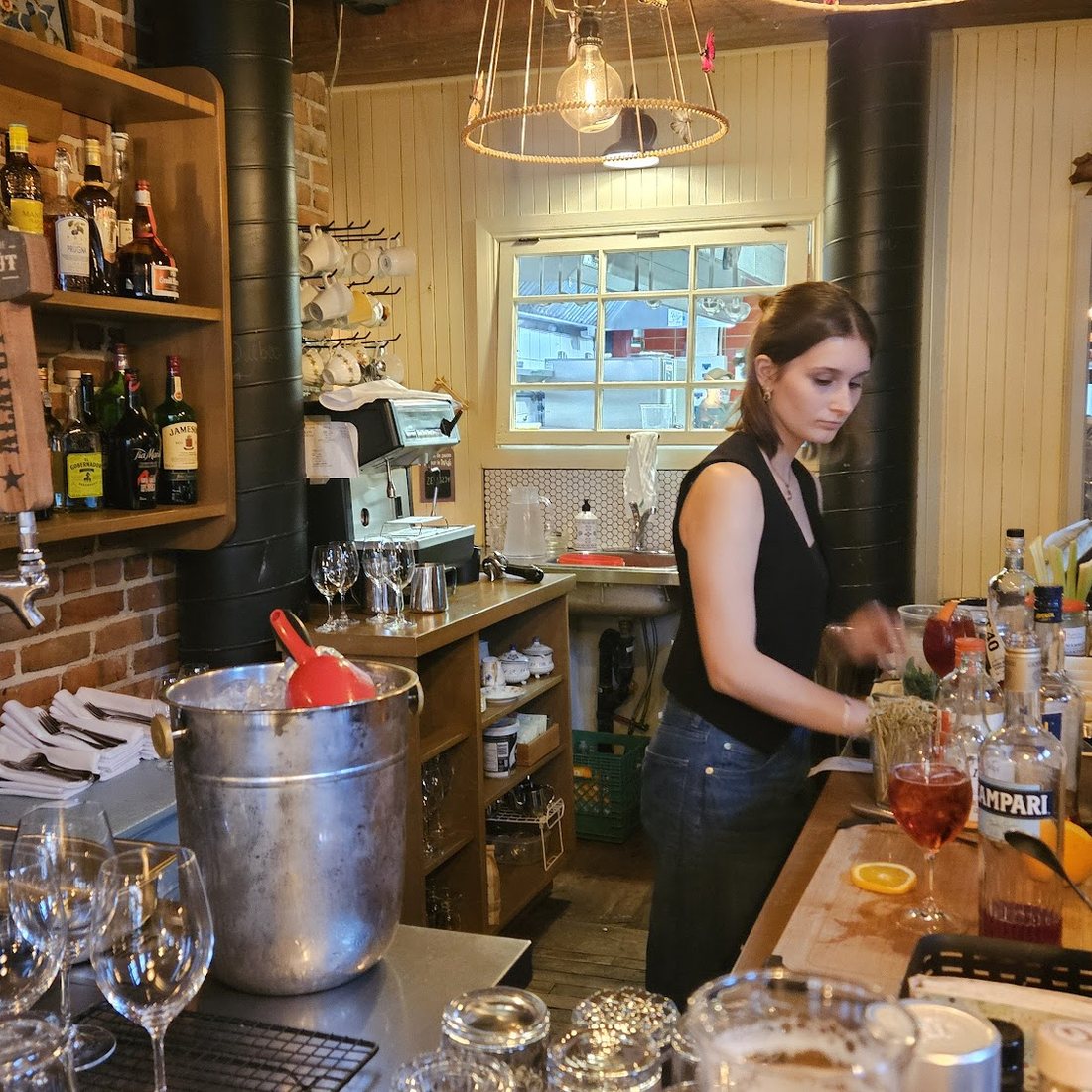 Le bar du Zélé, ses bouteilles sur étagère de bois et le mur de brique