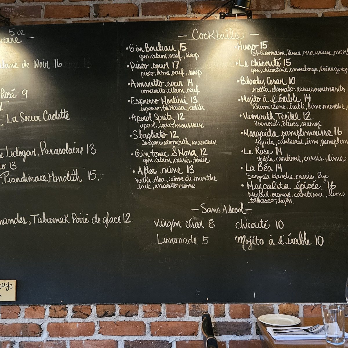 Le tableau des cocktails au-dessus du bar, écrit à la craie sur deux colonnes
