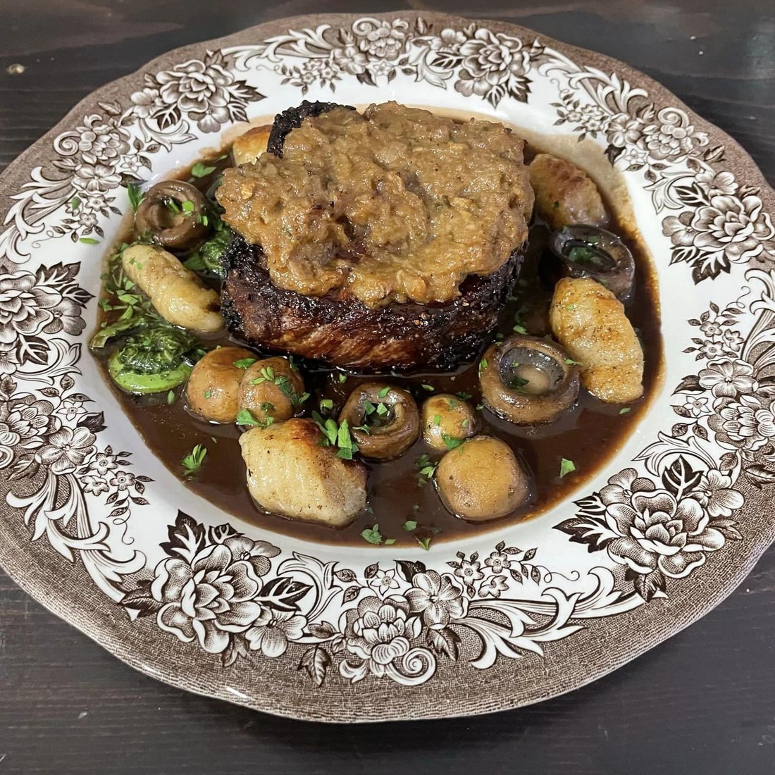 Le contre-filet servi avec champignons, choux de Bruxelles et pommes de terre, sur une assiette ancienne à motifs