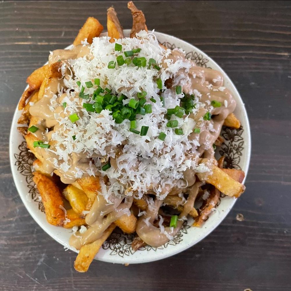 Les frites à l'ail noir, recouvertes de fromage râpé et de ciboulette